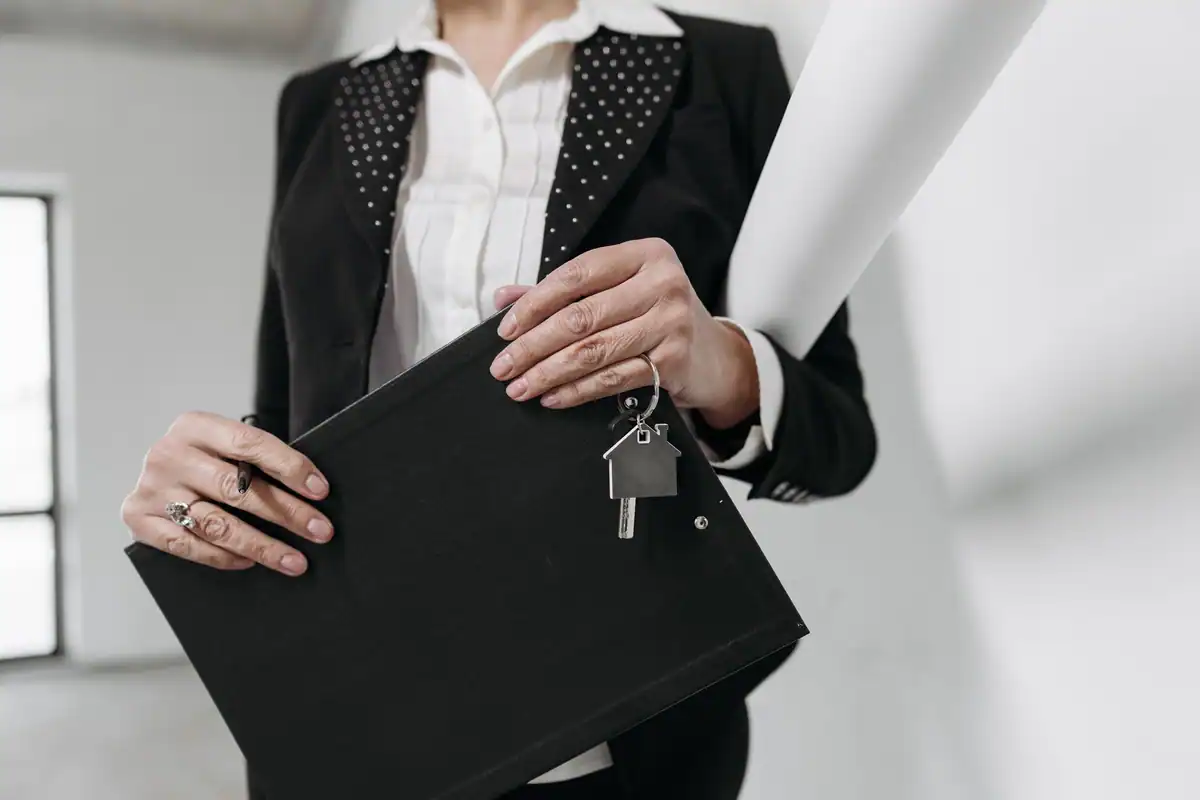 Agent imobiliar care ține un clipboard și o legătură de chei într-un birou