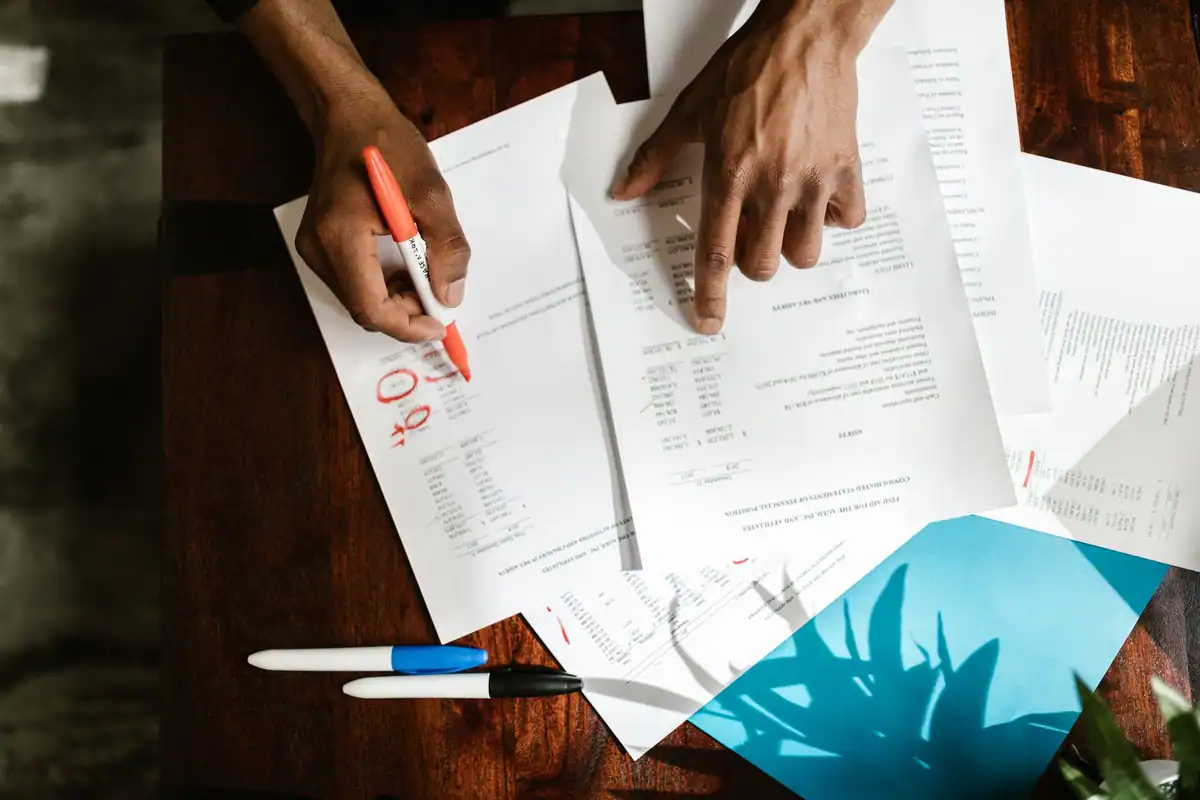 Mâini care subliniază cifre importante într-un document financiar pe birou