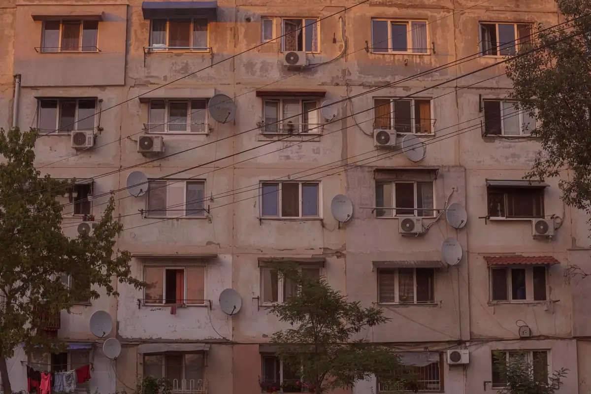 Fațadă uzată a unui bloc vechi cu aparate de aer condiționat și antene