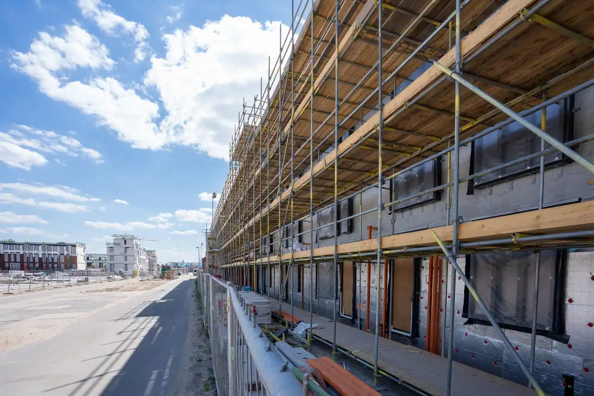 Schele pe fațada unei clădiri noi aflate în construcție, sub cer senin