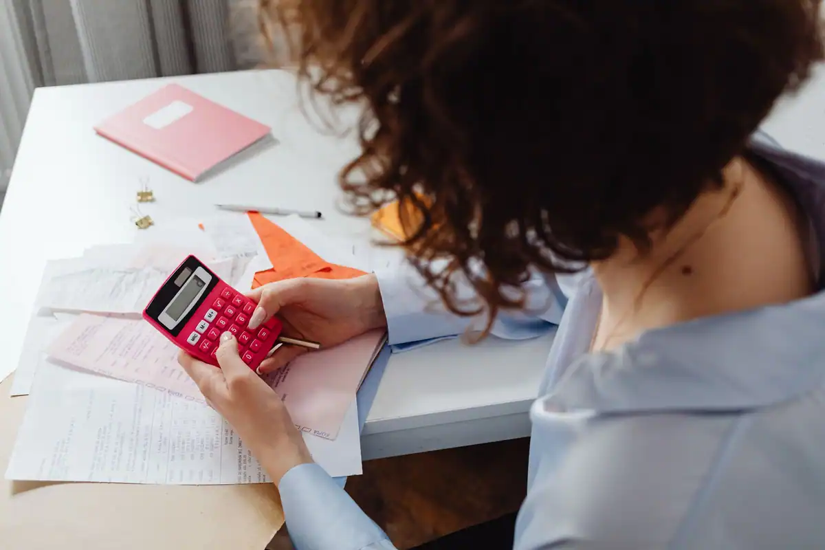 Femeie care calculează cheltuielile cu acte și calculator la biroul de lucru