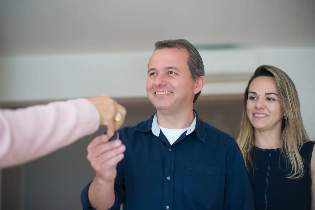 Cuplu zâmbitor care primește cheile noii locuințe după cumpărare