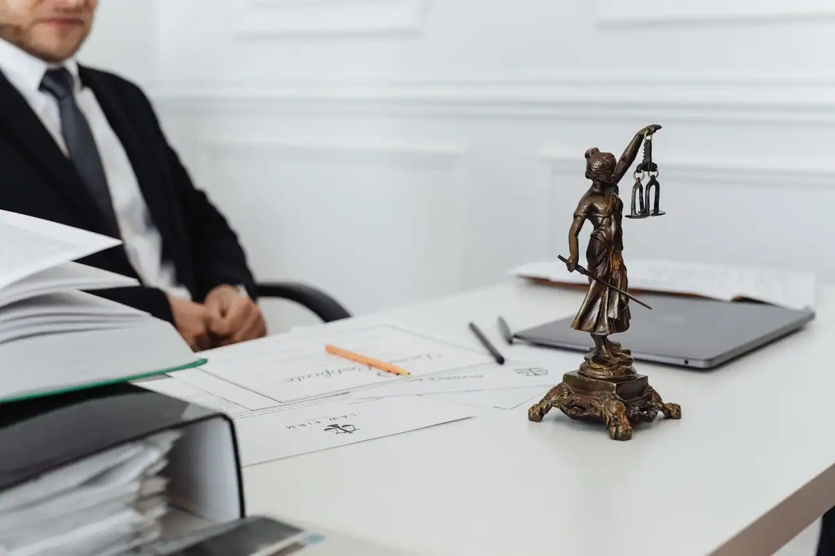 Birou de jurist cu statueta justiției, documente și laptop pentru verificarea actelor