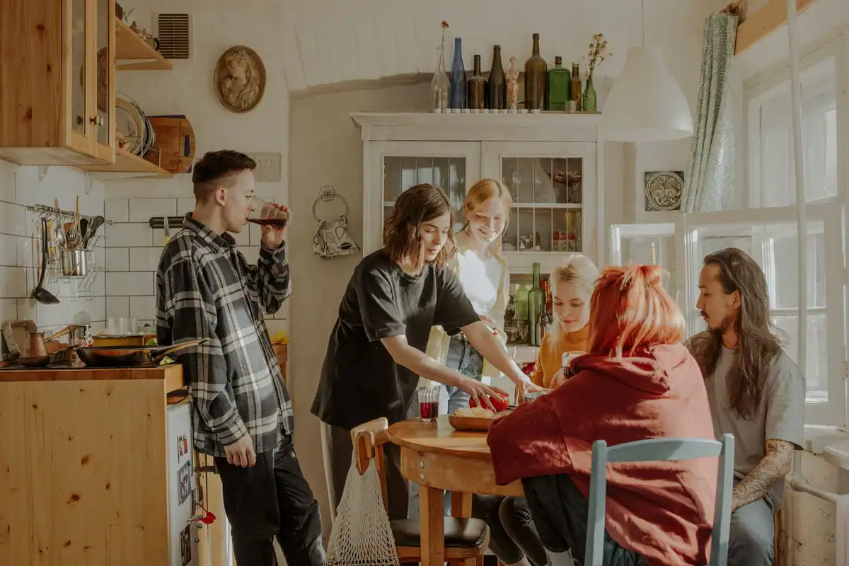 Prieteni care petrec un moment relaxat împreună într-o bucătărie însorită