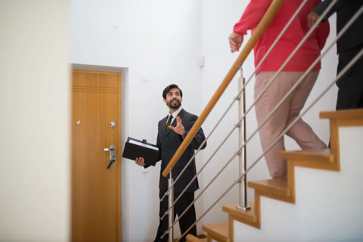 Agent imobiliar care conduce vizitatorii pe scările unei locuințe moderne