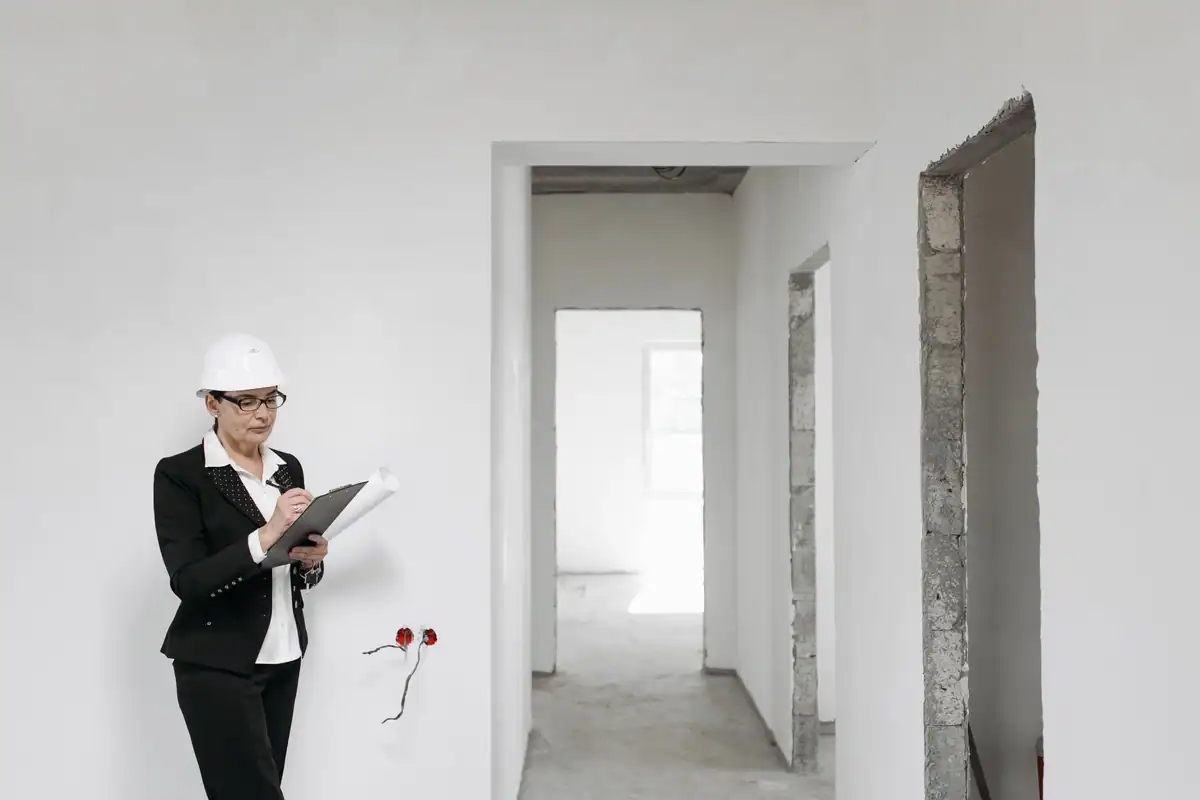 Arhitectă cu cască care inspectează pereții albi ai unui interior nefinisat